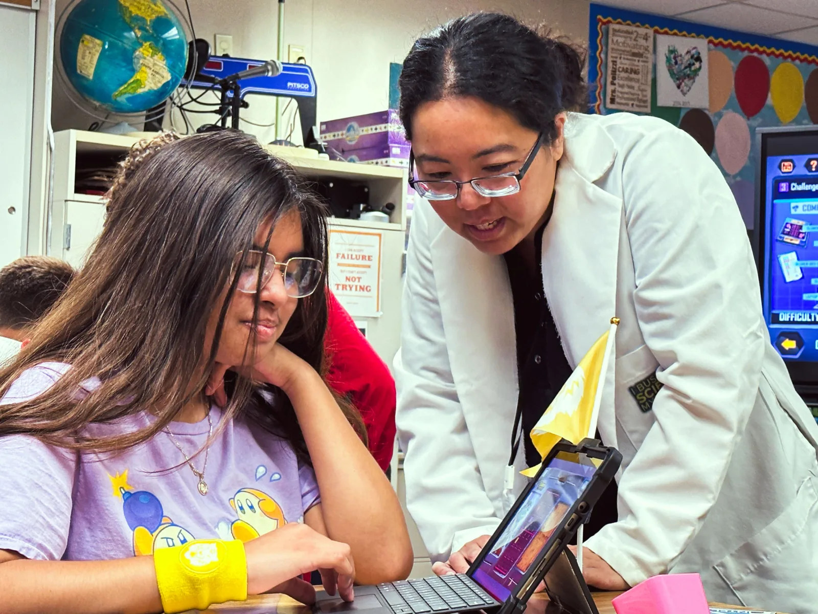 Facilitator supporting a student one-on-one with a tablet activity